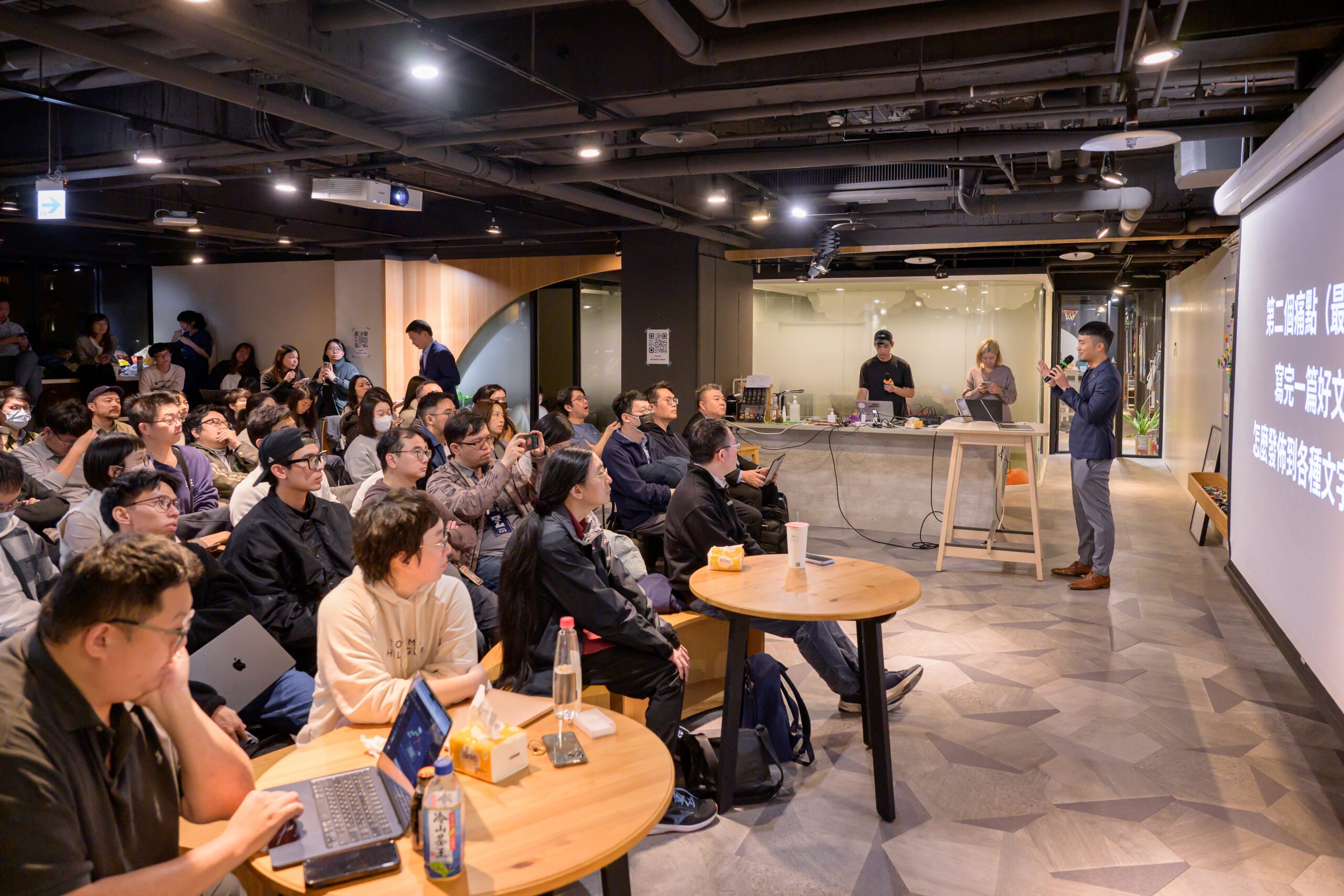 Generative AI 三月小聚全場約 70 位參加者坐在圓桌旁專注聆聽演講